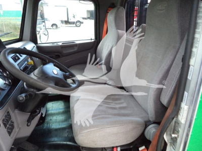 Truck cab interior with steering wheel and two front seats visible, beige fabric seats, dashboard on left, door open.