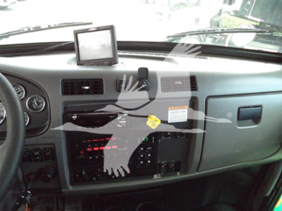 Peterbilt truck dashboard interior showing steering wheel, instrument panel, center console, aftermarket GPS unit on dash, various switches and warning labels.