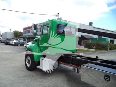 Truck image showing a green Peterbilt rollback truck with extended cab and crane, side view highlighting cab, chassis, and auxiliary equipment.