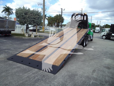Peterbilt 348 rollback tow truck with wooden ramp bed and green cab, side view showing loading deck and equipment.