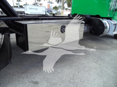 Peterbilt 348 rollback truck undercarriage showing black toolbox and hitch area with green cab visible in background.