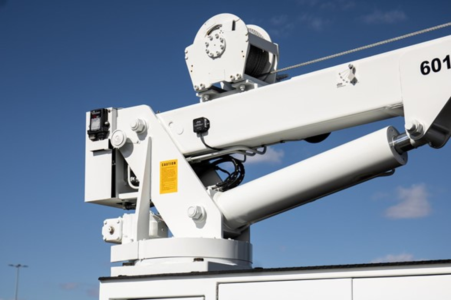 Boom lift arm and hydraulic piston on Freightliner truck utility crane showing white machinery and components.