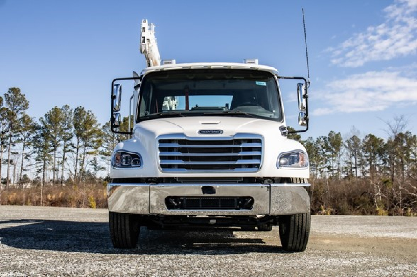 Front view of a white Freightliner M2 106 Plus service truck with chrome grille and bumper.