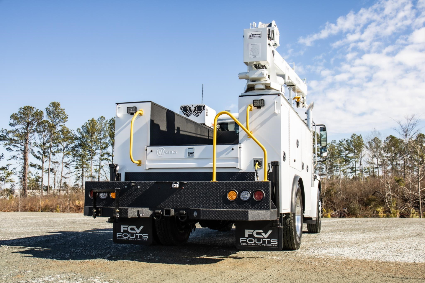 Freightliner M2 106 Plus service truck rear view showing utility bed, crane/boom, rear step, taillights, and FCV Fouts mud flaps.