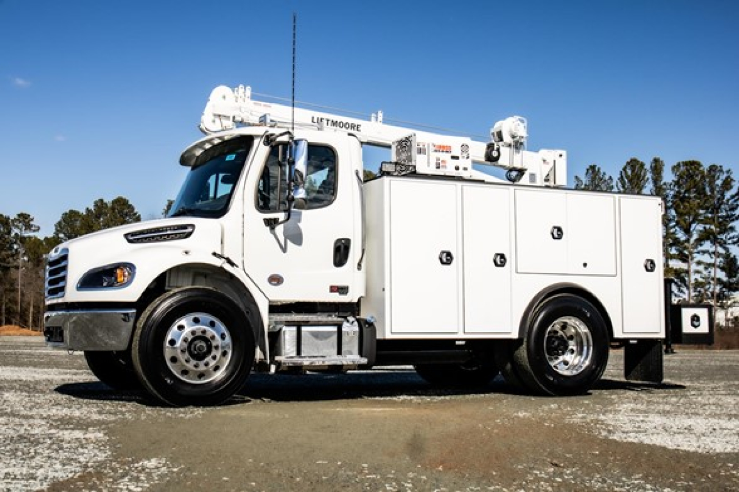 Freightliner M2 106 Plus service/utility truck with utility boxes and crane, side view.