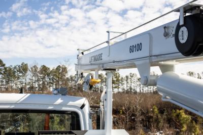 Truck cab and crane jib with Liftmoore branding and model number 60100 visible on boom, hydraulic components and winch assembly in the foreground.