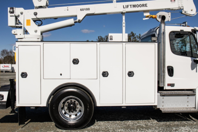 Service/utility truck body on Freightliner M2 106 Plus with multiple storage compartments and utility crane arm visible on top; side profile shows wheel and doors.