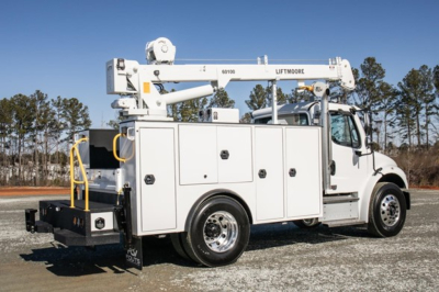 Service/Utility truck in profile with bucket lift arm extended, multiple storage compartments, white exterior, Freightliner M2 106 Plus chassis.