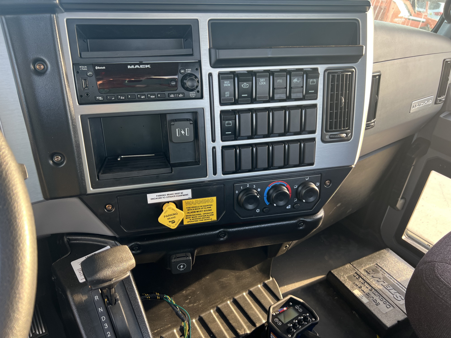 Mack MD6 truck dashboard/center console with multiple switches, radio, climate controls, and storage compartments visible.