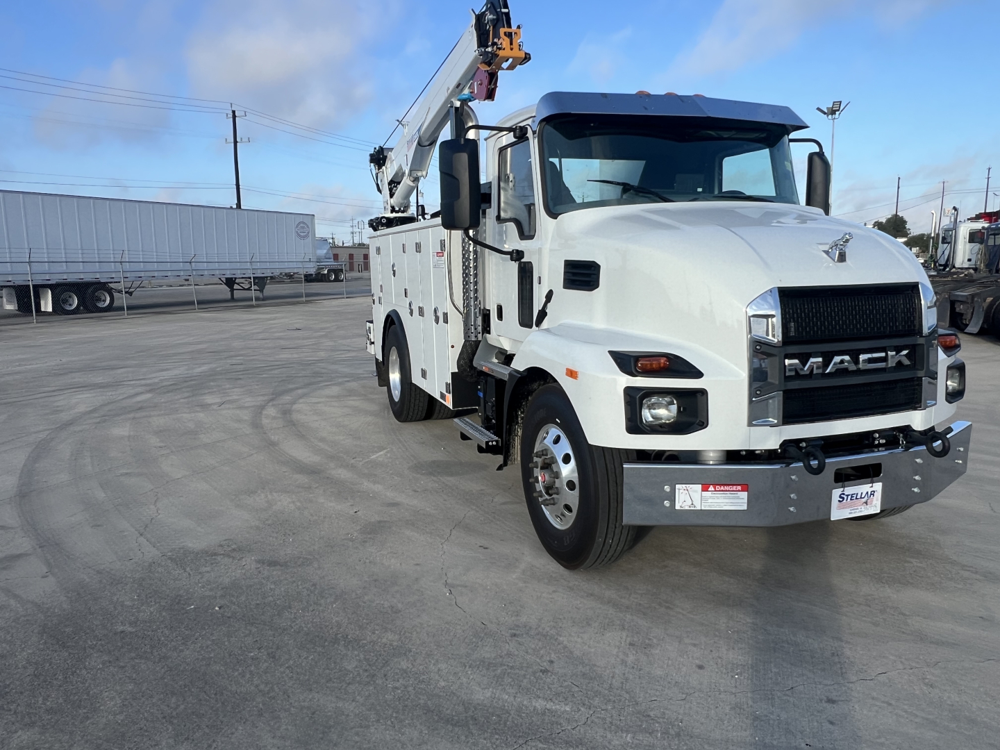 Front-left view of a white 2026 Mack MD6 tow truck with crane, showing Mack grille and bumper, headlights, and service body.
