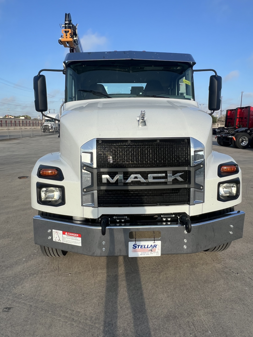 Front view of a white 2026 Mack MD6 dump truck showing 'MAC K' grille, large bumper, headlights, and crane in background.