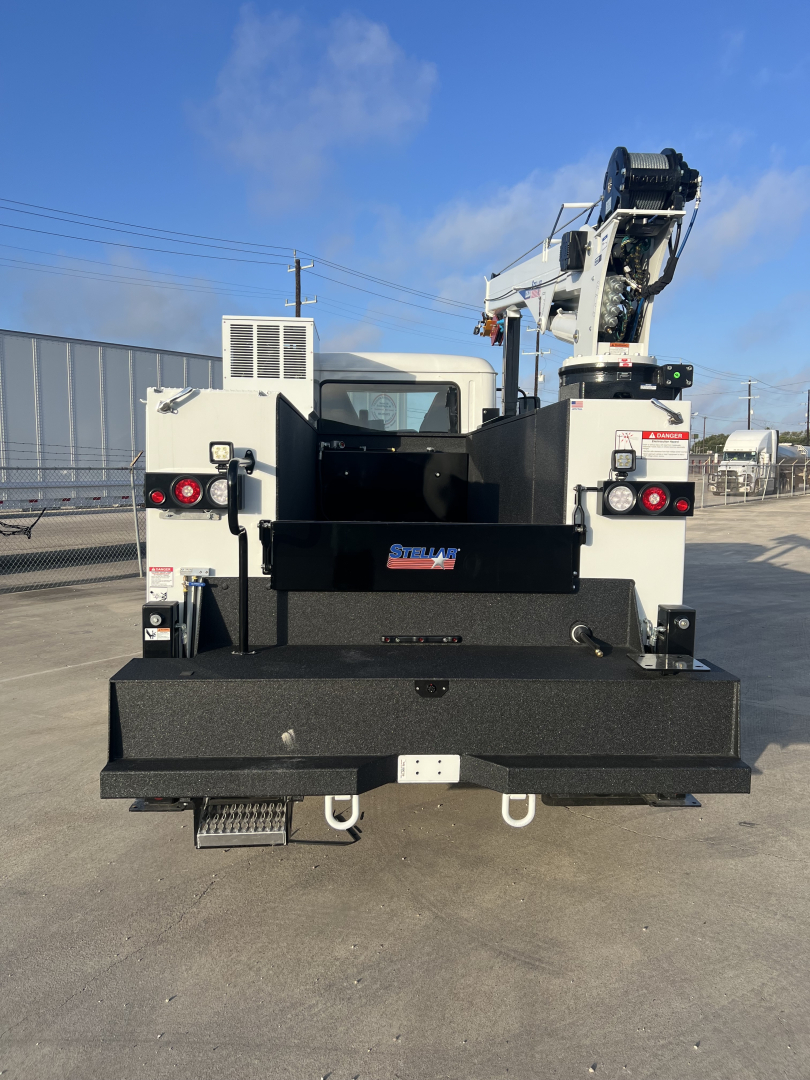 Rear view of a white Mack MD6 service truck with crane, flatbed and steps, showing fleet equipment and bumper details.