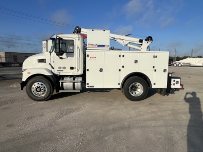 White Mack MD6 utility service truck with hydraulic crane mounted on top, side compartments, cab with door, and dual rear wheels.