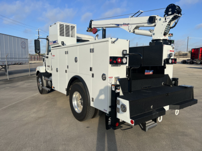 New Mack MD6 service truck with crane and utility boxes, rear winch platform, multiple storage compartments, side mirrors, and crane arm folded over bed.
