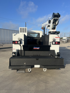 Rear view of a white Mack MD6 service truck with crane, flatbed and steps, showing fleet equipment and bumper details.