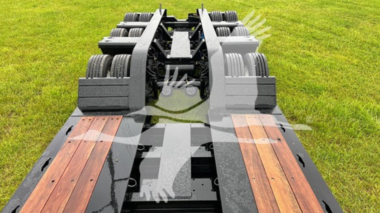 Lowboy trailer deck showing heavy-duty wooden planks and dual axle assemblies with multiple tires.
