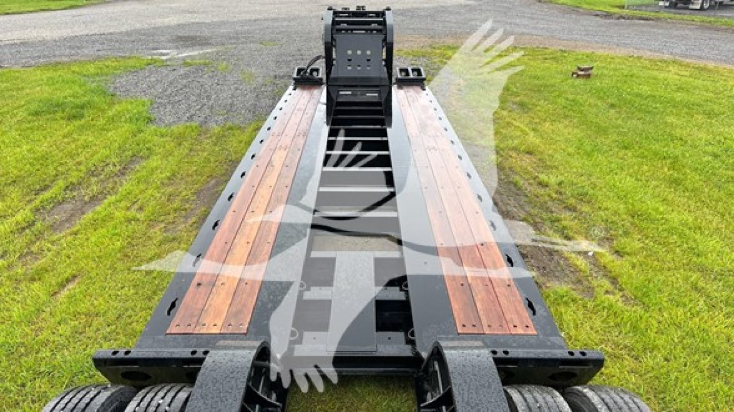 Fontaine lowboy trailer frame showing bolster and wooden deck with central gooseneck, front view.