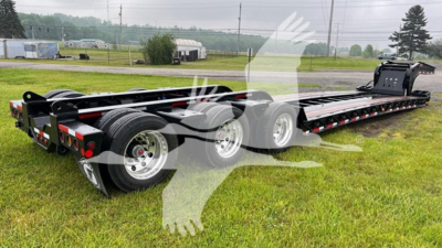 Fontaine 55 LCC lowboy trailer showing long flatbed with multiple axles and chrome wheels, empty bed, in a grassy lot.
