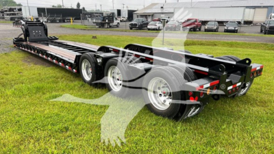 Fontaine lowboy trailer in a yard showing long black flatbed with multiple axles and label plates, rear lighting, and tandem wheels.