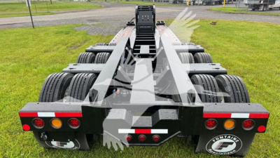 Lowboy trailer rear view showing tandem axle arrangement and extended frame with landing gear, round taillights, and black chassis.