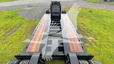 Fontaine lowboy trailer frame showing bolster and wooden deck with central gooseneck, front view.