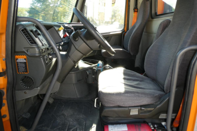Volvo VNR64T300 truck cab interior showing steering wheel, dashboard, and two fabric seats with gear shift and orange accents.