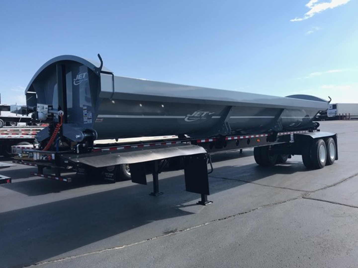 Jet 40' air ride side dump trailer on a flatbed with tandem axles, gray exterior, side-mounted hydraulic system, Jet logo visible.
