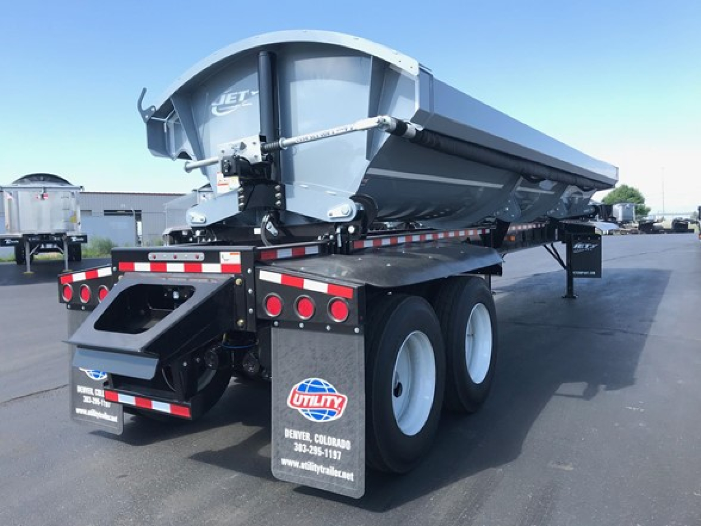 Jet Jet Air Ride Side Dump trailer in a side view showing rear bumper, dual rear wheels, and hydraulic dump mechanism. Text on rear shows UTILITY branding and Arkansas dealer sticker.