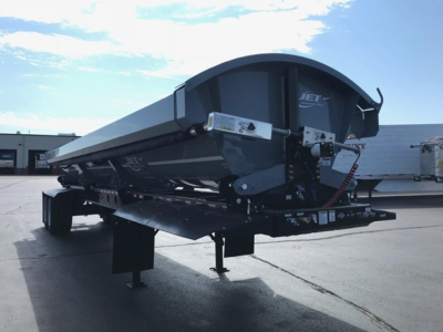 Jet air ride side dump trailer on a hitch, with hydraulic lines and support jacks visible, showing the curved front end and side panels.