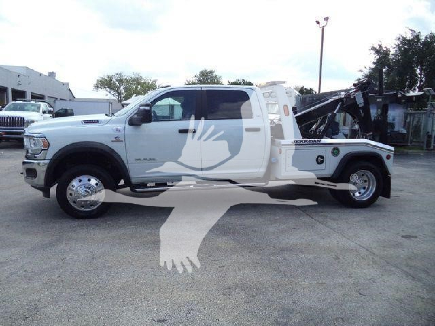 Ram 5500 tow truck with a crane in white, side view showing extended cab and winch equipment.