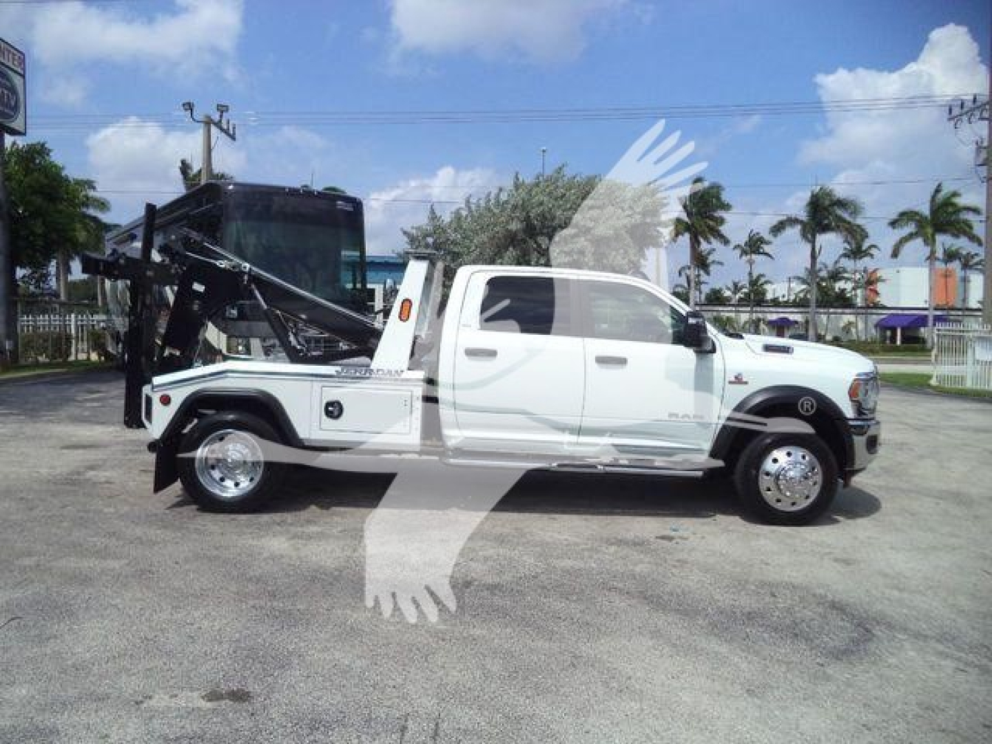 Ram 5500 pickup with front cab doors open, hydraulic tow/tilt bed and winch equipment in a dealership lot.