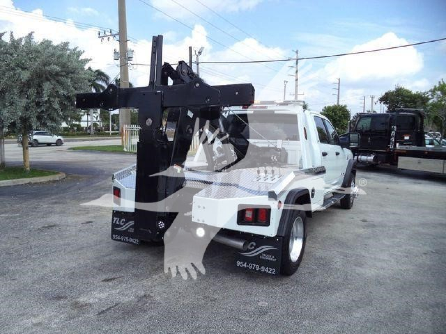 Truck bed with a mounted hydraulic winch system on a white Ram 5500 chassis, rear view showing winch frame and mounting hardware.