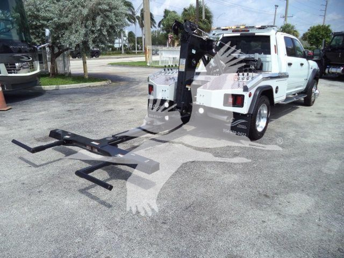 Ram 5500 pickup with winch and ladder rack showing mounted tow hitch and long-arm fork attachment in truck bed area.