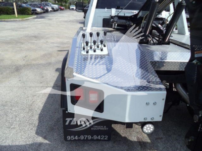 Ram 5500 winch truck rear deck with control levers on polished diamond plate and bumper-mounted light; visible 'TRUCK & EQUIPMENT' watermark and contact number.