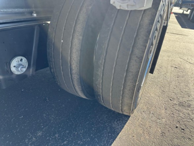 Mac all-aluminum drop deck trailer wheel close-up showing dual tires and suspension edge under deck.