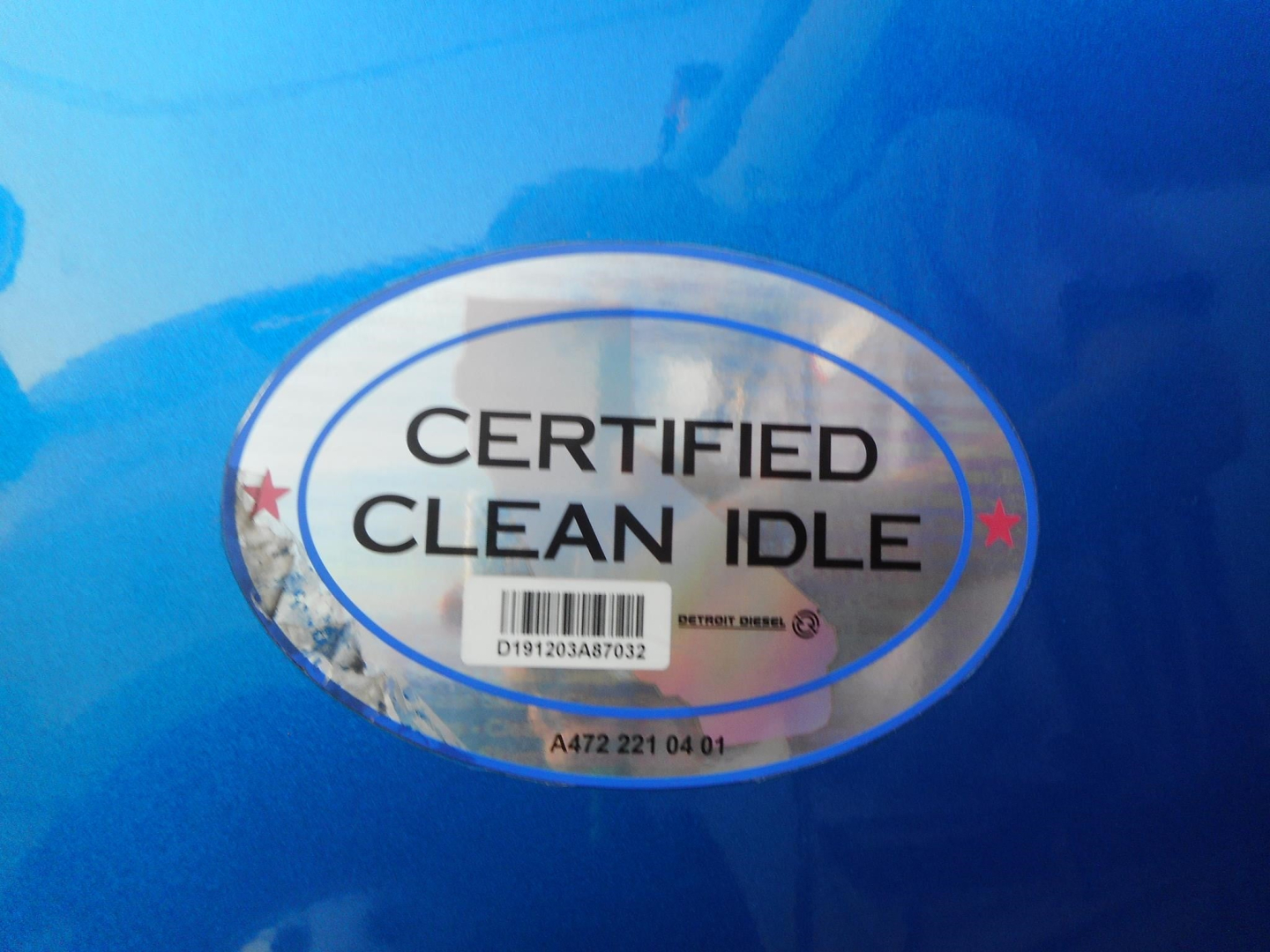 Certified Clean Idle badge sticker on blue truck surface with serial numbers and small barcode