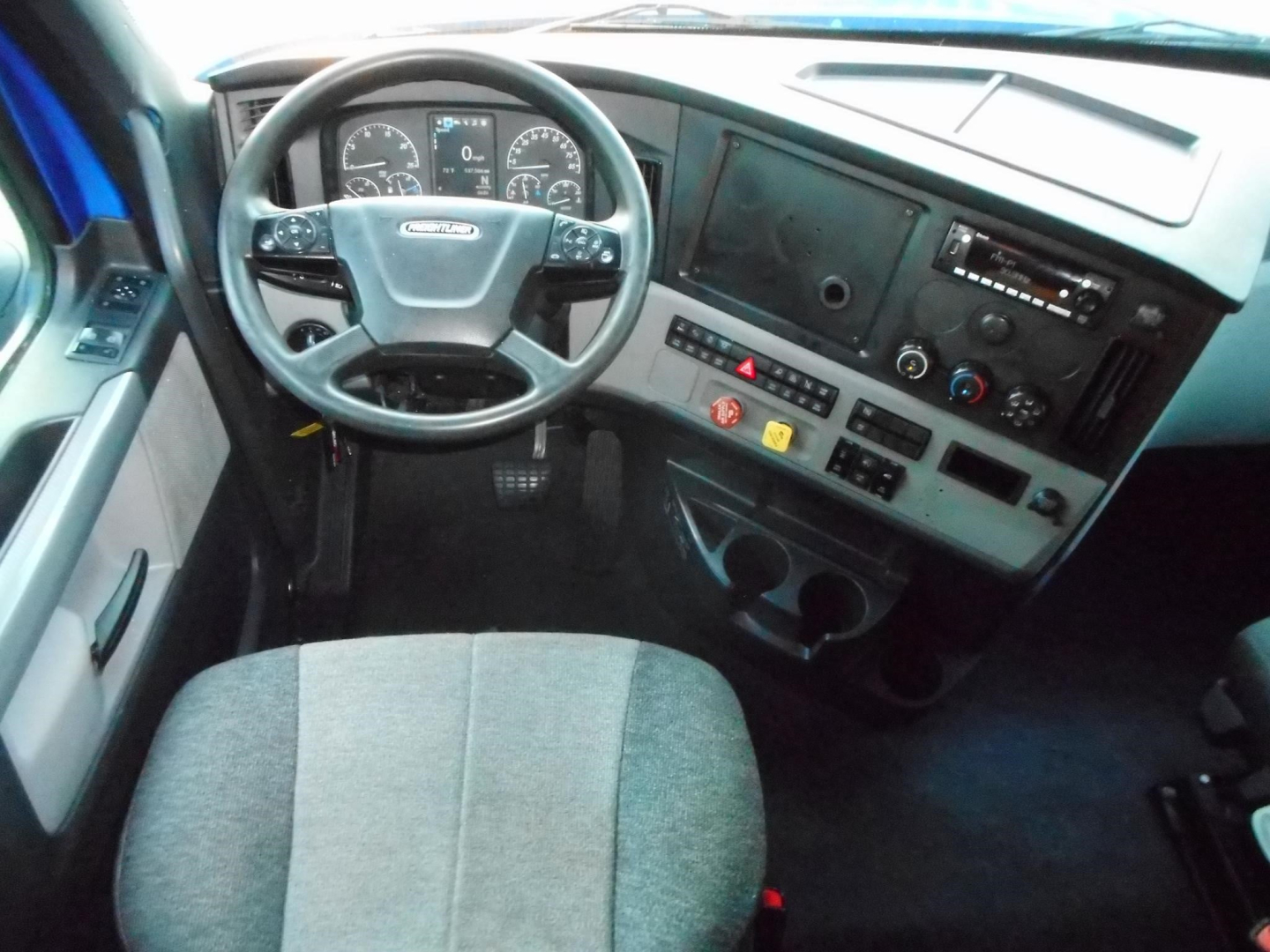 Cab interior of a 2022 Freightliner Cascadia 126 showing steering wheel, dashboard, and driver's seat.