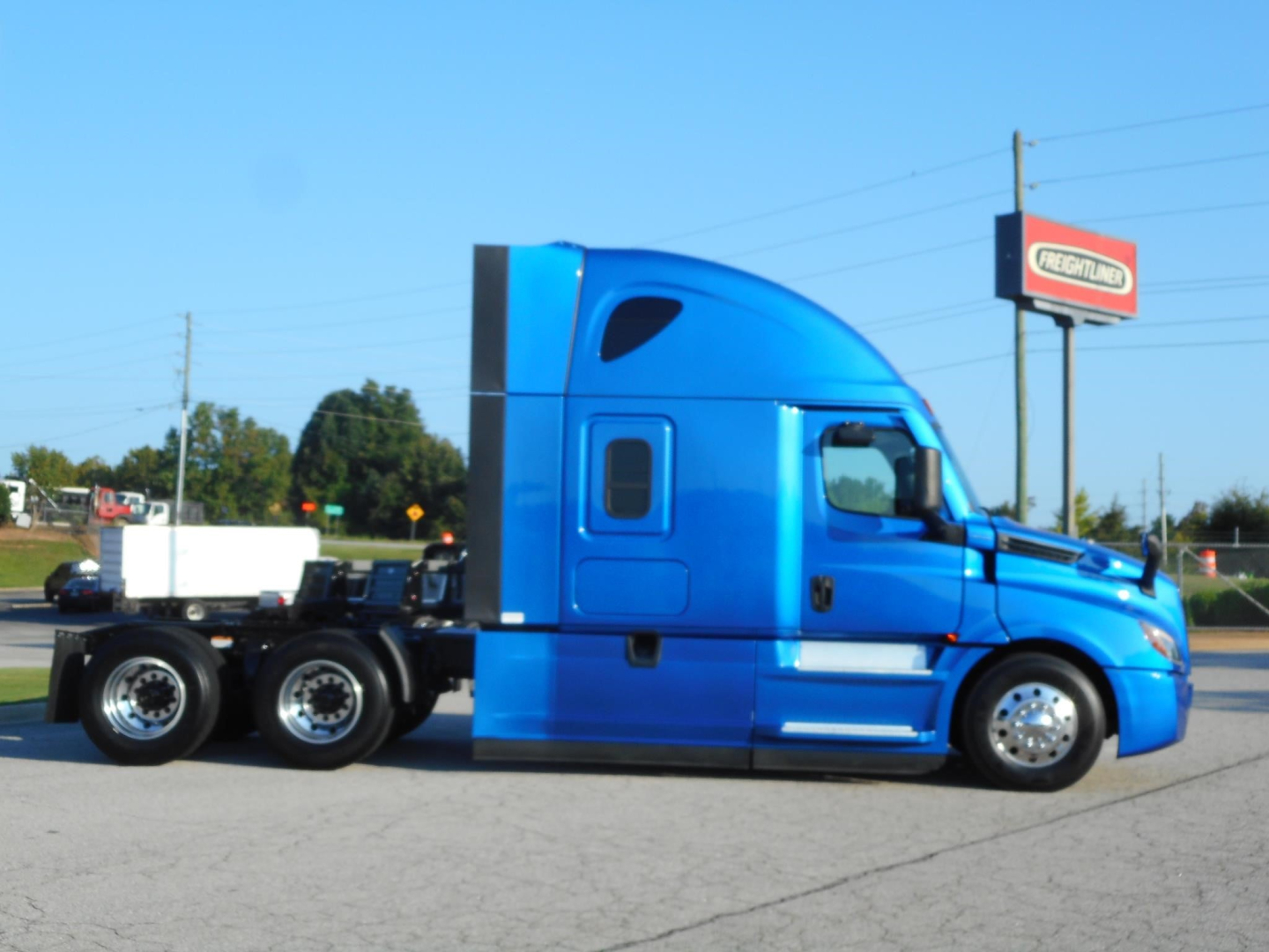 Blue Freightliner Cascadia 126 tractor from side view, 6x4 configuration, with sleeper cab and chrome wheels.