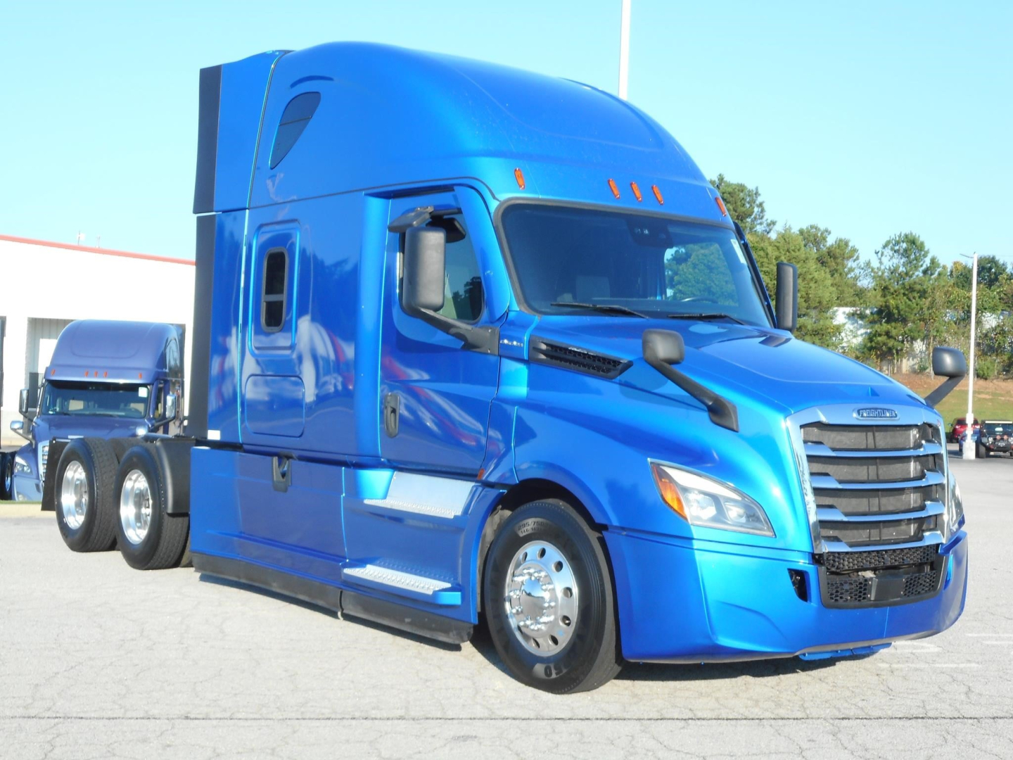 Blue Freightliner Cascadia 126 conventional sleeper truck, front three-quarter view showing chrome wheels and side mirrors.