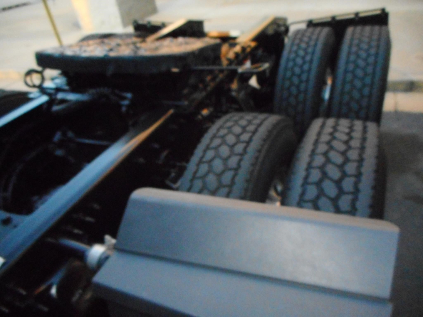 Freightliner Cascadia chassis showing dual rear axles and tires, engine bay area visible with cab removed parts.