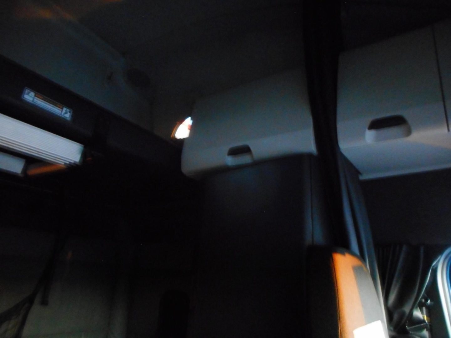 Freightliner Cascadia interior with sleeper cabin doors and curtains visible; partial dashboard area.