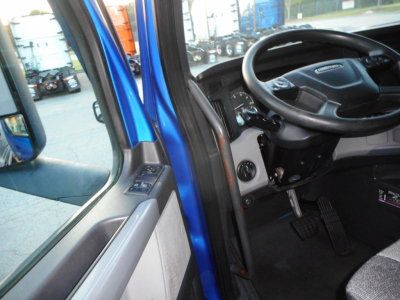 Cab interior of a Freightliner Cascadia 126 truck showing steering wheel, driver's seat, pedals, and door panel.