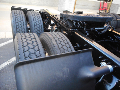 Truck chassis showing rear dual axles and leaf springs with tires and frame rails.