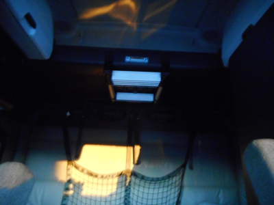 Cab interior showing under-dash storage and a small white object; dim lighting.