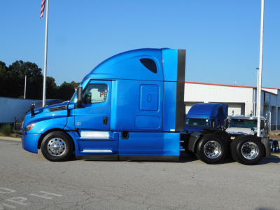 Blue Freightliner Cascadia 126 sleeper cab tractor in a lot, side profile view with chrome wheels and black rear dual axles.