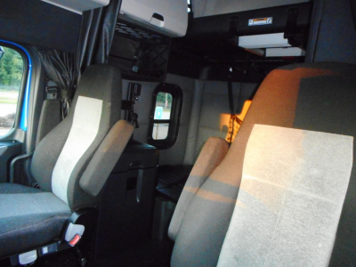 Truck cab interior of a 2022 Freightliner Cascadia 126 with driver and passenger seats, overhead storage, and cabin area visible.