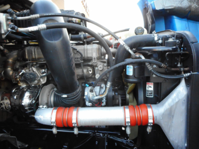 Freightliner Cascadia engine bay showing turbocharger, piping, and red-banded intercooler pipe.