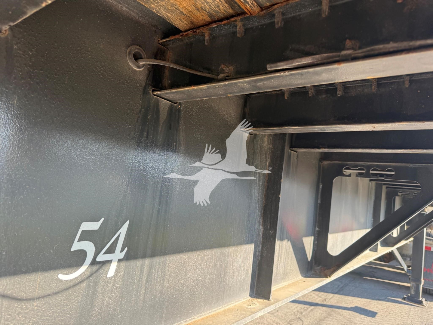Trailer side with number 54 and Fontaine logo on black metal surface, showing part of the underframe and support beams.