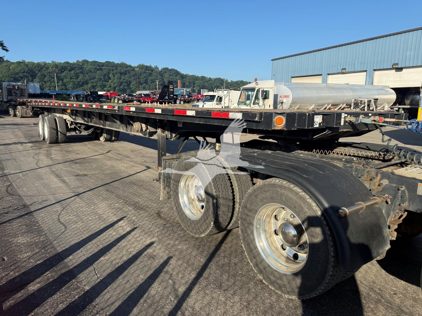 Flatbed trailer showing dual rear axles and long deck with side rails, Fontaine XTP 4880SS2 trailer in a yard.