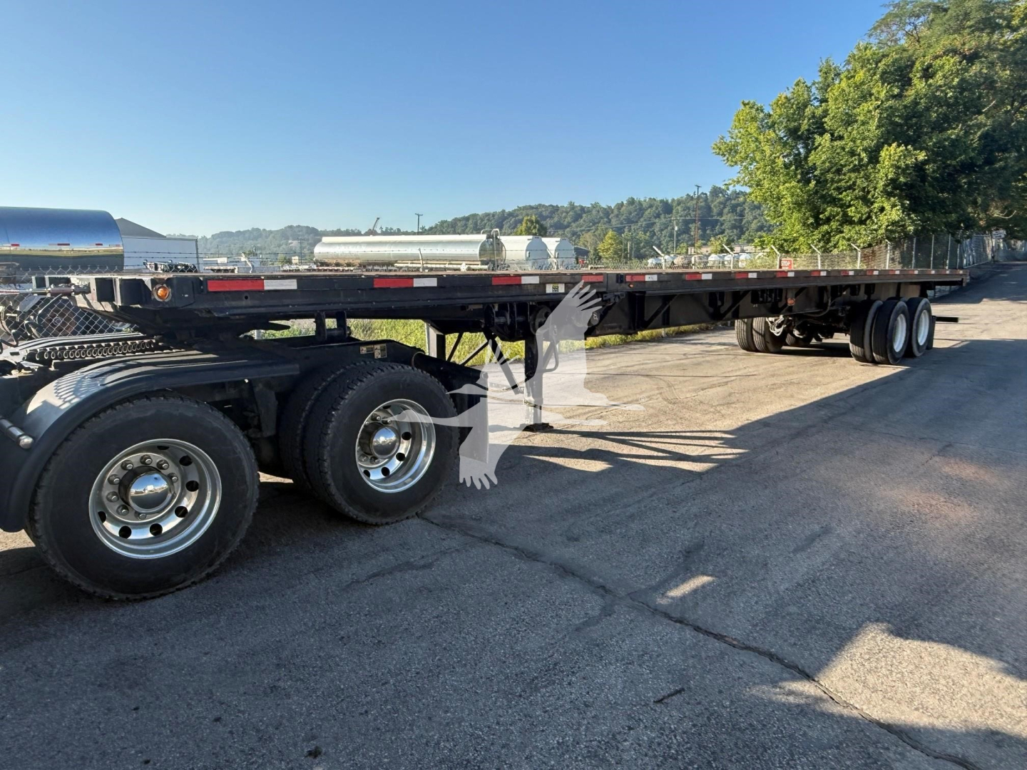 Flatbed trailer with dual rear axles and long deck, Fontaine XTP 4880SS2 style, parked on lot. Visible components include wheels, black deck, and support frames.